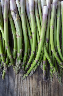 Tahta arka planda taze, yeşil, sağlıklı, çiğ kuşkonmaz.