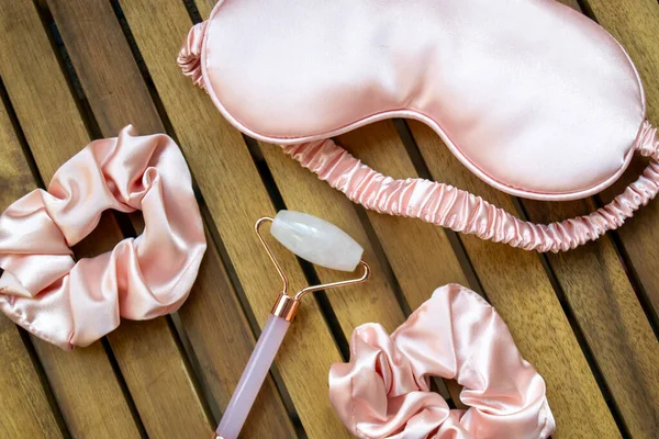 Yumuşak ipeksi pembe uyku maskesi, saç tokası ve kuvars silindirli.