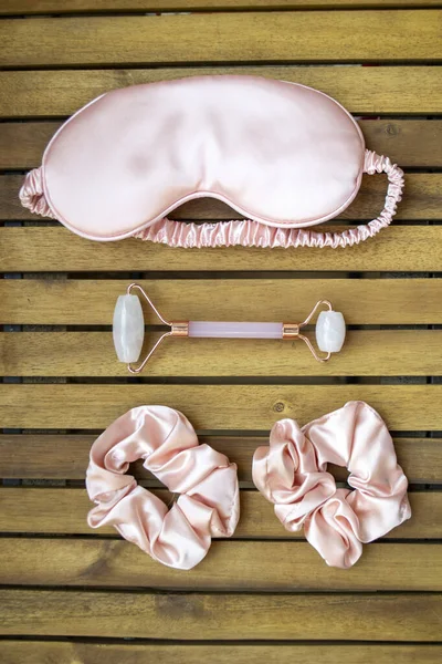 Yumuşak ipeksi pembe uyku maskesi, saç tokası ve kuvars silindirli.