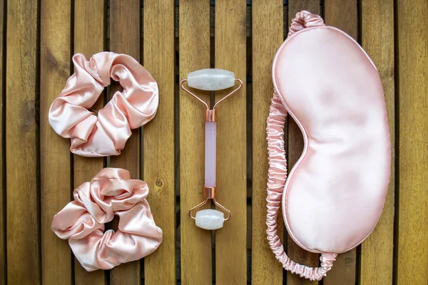 Yumuşak ipeksi pembe uyku maskesi, saç tokası ve kuvars silindirli.