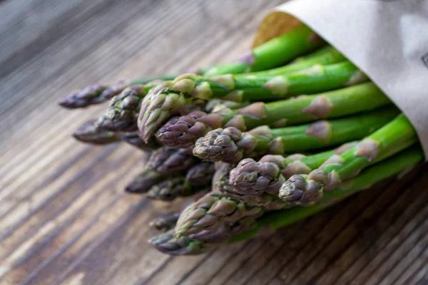 Tahta arka planda taze, yeşil, sağlıklı, çiğ kuşkonmaz.