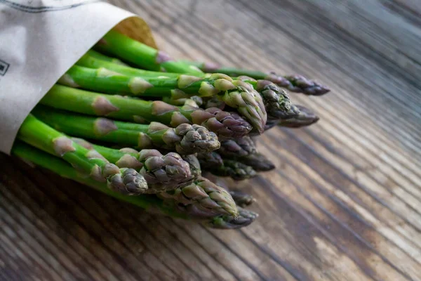 Tahta arka planda taze, yeşil, sağlıklı, çiğ kuşkonmaz.