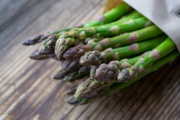Tahta arka planda taze, yeşil, sağlıklı, çiğ kuşkonmaz.
