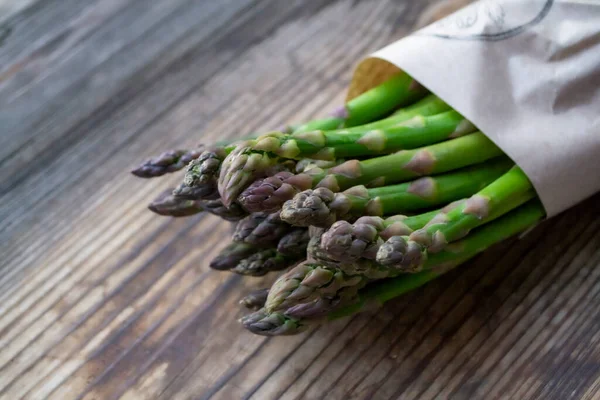 Tahta arka planda taze, yeşil, sağlıklı, çiğ kuşkonmaz.