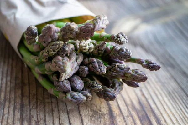Tahta arka planda taze, yeşil, sağlıklı, çiğ kuşkonmaz.