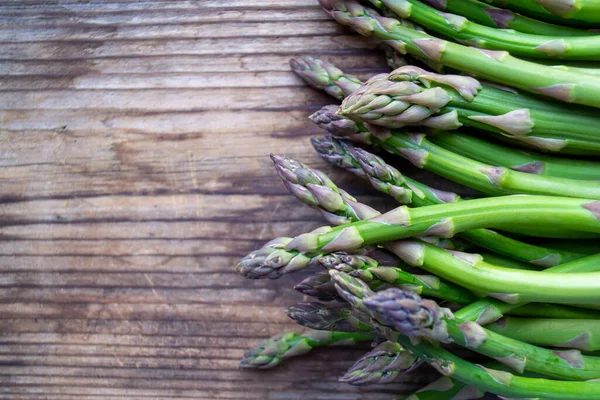 Tahta arka planda taze, yeşil, sağlıklı, çiğ kuşkonmaz.