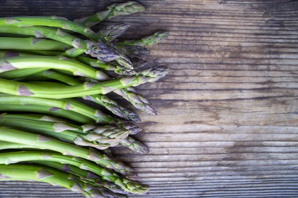 Tahta arka planda taze, yeşil, sağlıklı, çiğ kuşkonmaz.