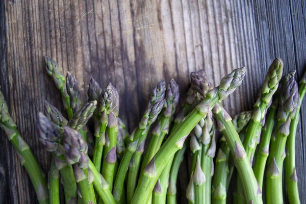 Tahta arka planda taze, yeşil, sağlıklı, çiğ kuşkonmaz.