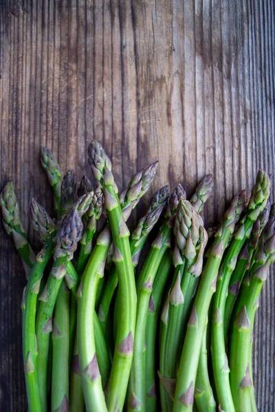 Tahta arka planda taze, yeşil, sağlıklı, çiğ kuşkonmaz.