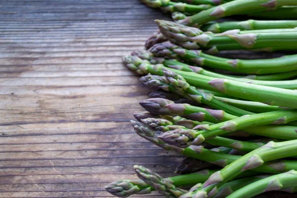 Tahta arka planda taze, yeşil, sağlıklı, çiğ kuşkonmaz.