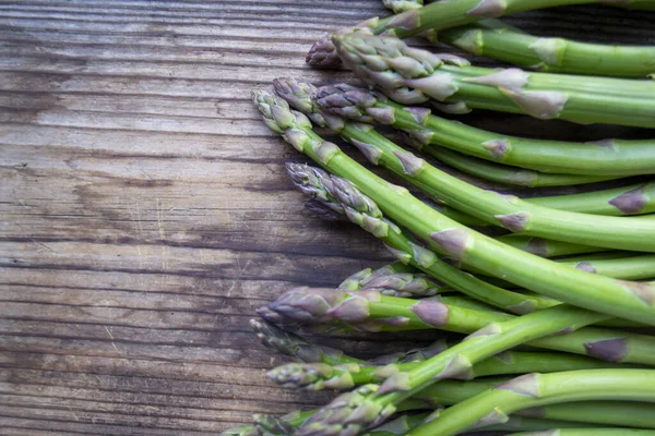 Tahta arka planda taze, yeşil, sağlıklı, çiğ kuşkonmaz.