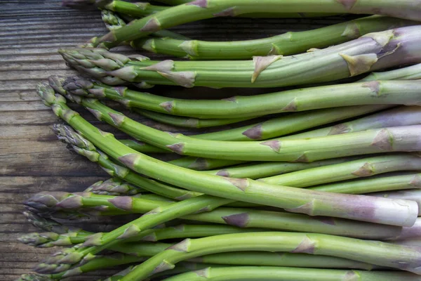 Tahta arka planda taze, yeşil, sağlıklı, çiğ kuşkonmaz.
