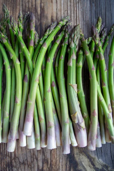 Tahta arka planda taze, yeşil, sağlıklı, çiğ kuşkonmaz.