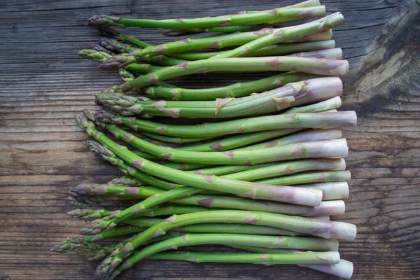Tahta arka planda taze, yeşil, sağlıklı, çiğ kuşkonmaz.