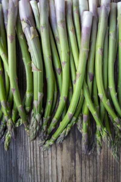 Tahta arka planda taze, yeşil, sağlıklı, çiğ kuşkonmaz.