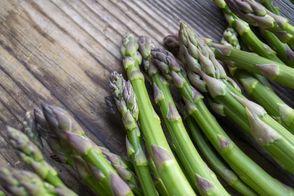 Tahta arka planda taze, yeşil, sağlıklı, çiğ kuşkonmaz.