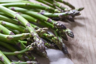 Tahta arka planda taze, yeşil, sağlıklı, çiğ kuşkonmaz.
