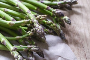 Tahta arka planda taze, yeşil, sağlıklı, çiğ kuşkonmaz.