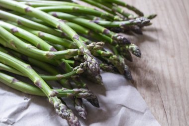 Tahta arka planda taze, yeşil, sağlıklı, çiğ kuşkonmaz.