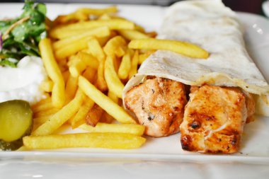 Büyük beyaz tabak tavuk eti pide ekmek, turşu, salata ve sos ile patates kızartması,