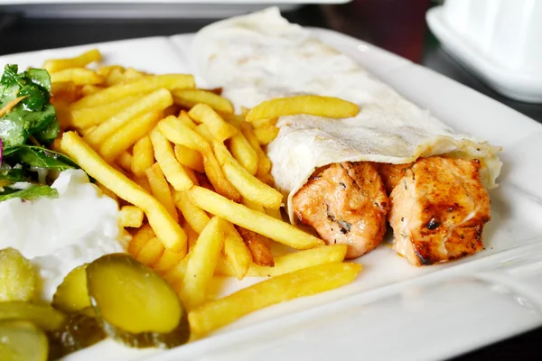 Big white plate with French fries, chicken meat in pitta bread, pickles, salad and sauce — Stock Photo, Image