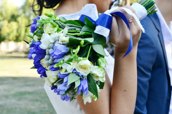 Hermosa novia sosteniendo un ramo de boda de albaricoque y rosas azules — Foto de Stock