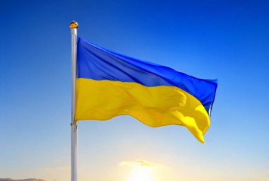 Ukrayna 'nın ulusal sarı ve mavi bayrağı güneşin doğuşu ve açık bir gökyüzü üzerinde