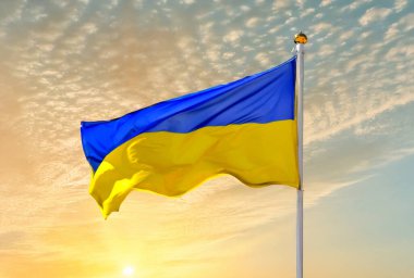 Ukrayna 'nın ulusal sarı ve mavi bayrağı güneşin doğuşu ve açık bir gökyüzü üzerinde