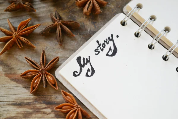 Een lege retro spiraal notebook met oud papier met een hote dat mijn verhaal en anijs sterren op houten tafel zegt — Stockfoto