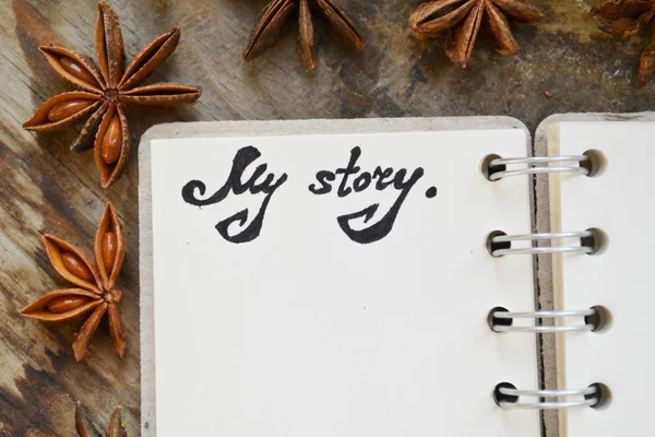 Een lege retro spiraal notebook met oud papier met een hote dat mijn verhaal en anijs sterren op houten tafel zegt — Stockfoto