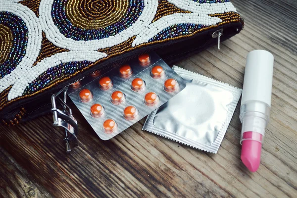 Couple de préservatifs et un ensemble de cosmétiques avec rouge à lèvres rose et friseur de cils — Photo