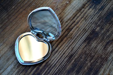 Sevimli küçük cep aynası ahşap masa üzerinde kalp şeklinde