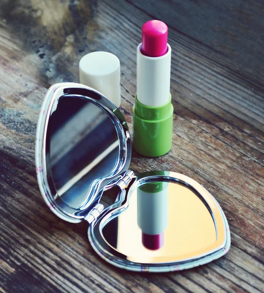 Lindo espejo de bolsillo en forma de corazón con lápiz labial rosa en la mesa de madera —  Fotos de Stock