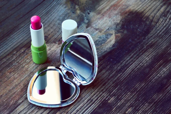 Schattige kleine zak spiegel in de vorm van hart met roze lippenstift op houten tafel — Stockfoto