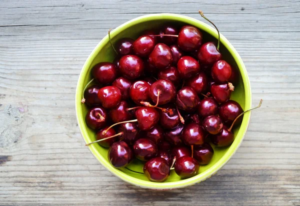 Lots of fresh and tasty dark sweet cherries in a green bowl — Stock Photo, Image