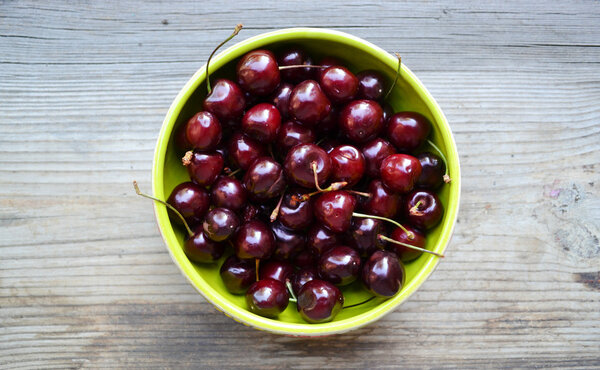 Lots of fresh and tasty dark sweet cherries in a green bowl