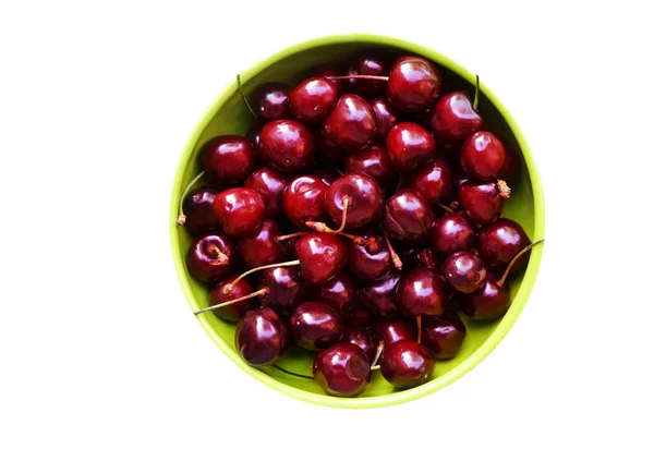 Lots of fresh and tasty dark sweet cherries in a green bowl isolated on white — Stock Photo, Image