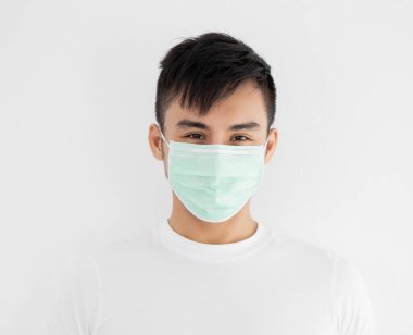 Beyaz arka planda cerrahi maske takan genç Asyalı adam, sağlık sigortası konsepti