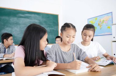 Bir grup Asyalı öğrenci ilkokulda sınıfta okuyor, eğitim konsepti