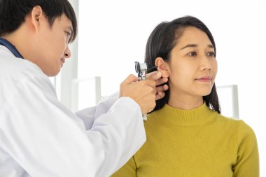 Audiologist examining young female patient ear using otoscope