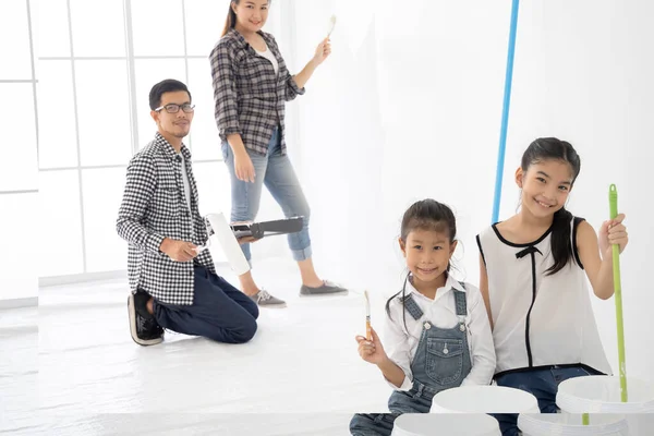 Happy family renovating their home. They are painting a wall together