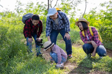 Asyalı aile, milli parkta yürüyüş yaparken birlikte eğleniyor, çocuklar için doğa eğitimi görüyor..
