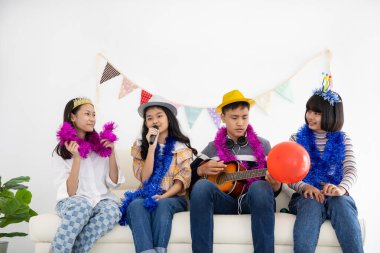 Mutlu Asyalı genç arkadaşlar evde şarkı söyleyip gitar çalıyorlar.