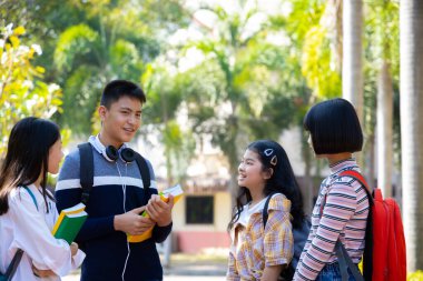 Okuldan sonra parkta eğlenen bir grup mutlu genç, eğitim kavramı.