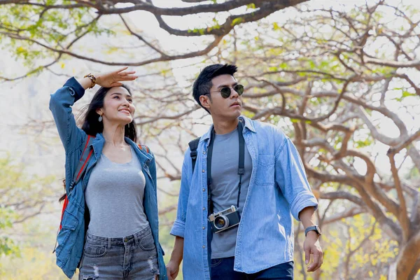 Young asian couple walking together with backpack in national park, camping and trekking concept