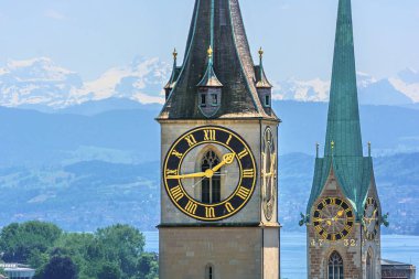 Saint Peter and Fraumnster Church in Zurich (Switzerland) in front of lake Zurich and the Swiss Alps clipart