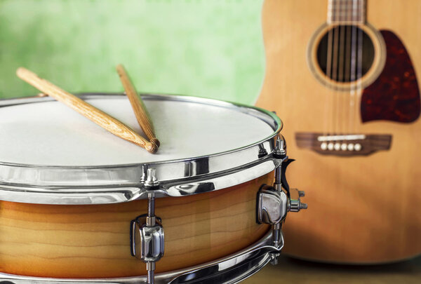 Snare drum and acoustic guitar on a green background