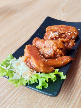 Appetizing Asian Glazed Chicken Wings Topped with White Sesame Seeds on Black Plate