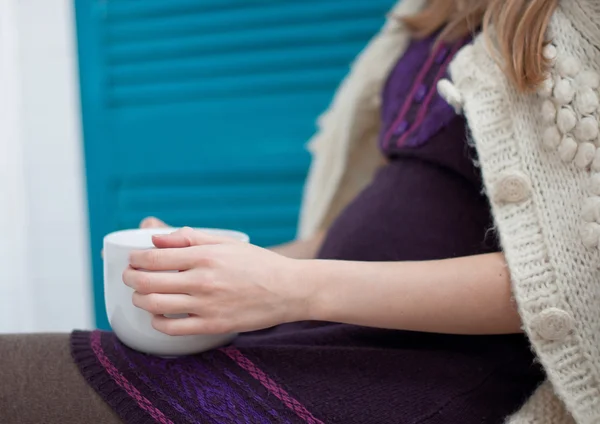 Беременная молодая женщина с чашкой горячего чая дома — стоковое фото