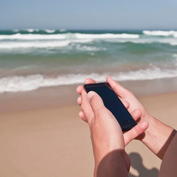 Smartphone nelle mani dell'uomo vicino all'oceano — Foto Stock